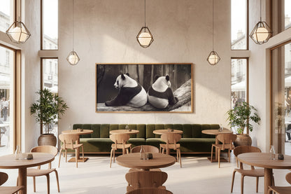 Large panda artwork with slim oak frame displayed above banquette seating in contemporary café interior.