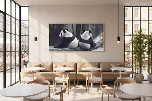Large panda artwork with slim oak frame displayed above banquette seating in contemporary café interior.