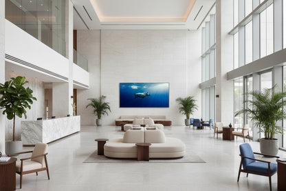 Oversized blue contemporary rhinoceros artwork displayed in a large reception area with high ceilings and natural light, white sculpted furniture, marble reception desk, plants
